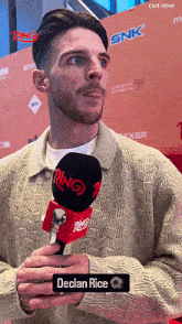 a man holding a microphone with the name declan rice on the bottom