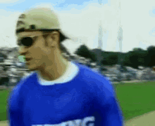 a man wearing a hat and sunglasses is wearing a blue shirt that says nyc on it