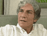 a close up of a man 's face with a white shirt on