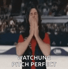a man is covering his mouth with his hands while watching a game .