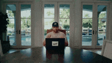a man sits at a table with a laptop with a sticker that says courage