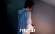 a man wearing headphones is standing in front of a wall with the words " the walls " on it