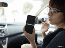 a woman in a car is holding a cell phone that says appmart on the screen