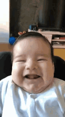 a baby is smiling while sitting in a high chair in a living room .