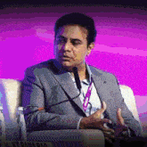 a man in a suit is sitting in front of a microphone with a name tag that says rama rao