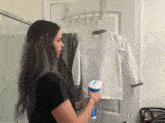 a woman is using a steamer to iron a white jacket