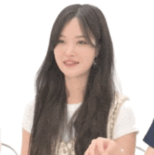 a close up of a woman with long hair wearing a white t-shirt and earrings .