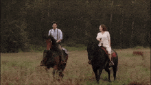 a man and a woman ride horses in a field