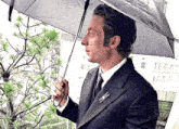 a man in a suit is holding an umbrella over a tree