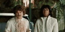 two men are standing next to each other and looking at something .