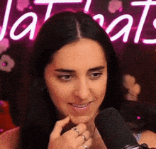 a woman is talking into a microphone in front of a neon sign that says ' a rat ' .