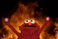 elmo is holding up two red circles with the number 1 on them in front of a fire