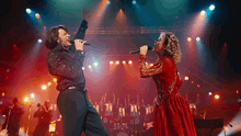a man and a woman singing on a stage with a crowd behind them