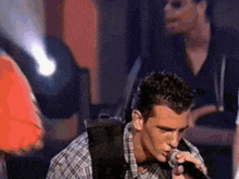 a man is singing into a microphone with a backpack on his back