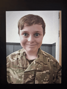 a young boy in a military uniform is smiling for the camera