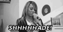 a black and white photo of a woman singing into a microphone with the words shhhhhade !