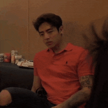 a man wearing a red polo shirt with a tattoo on his arm