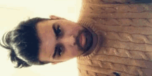 a man with a beard is wearing a sweater and looking at the camera .