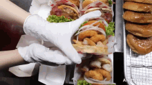 a person wearing white gloves takes a hamburger from a box