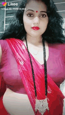 a woman in a red saree and a purple blouse is taking a selfie .
