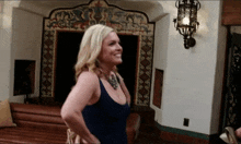 a woman in a blue dress stands in front of a wall