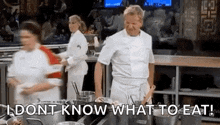 a man in a chef 's uniform is standing in a kitchen holding a pot and a spoon .