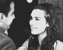a black and white photo of a man and a woman smiling at each other
