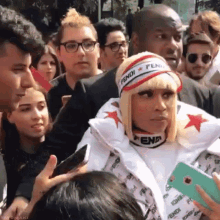 a woman wearing a fendi hat is surrounded by people