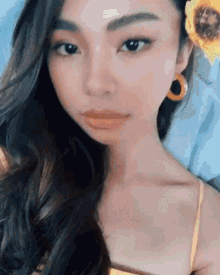 a woman with a sunflower in her hair takes a selfie