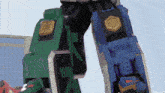 a blue and green robot with the letter t on its leg
