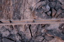 an aerial view of people walking on a bridge over a rocky cliff
