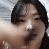 a close up of a woman 's face with a cotton ball on her nose .