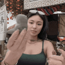 a woman in a green tank top is holding a rock