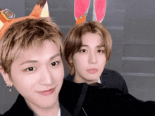 two young men are posing for a picture and one has bunny ears on
