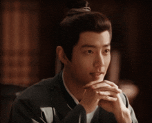 a close up of a man with his hands folded in front of his face .