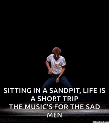 a man is sitting in a sandpit , life is a short trip the music is for the sad men .