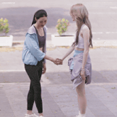 two women shaking hands in front of a sign that says lingormei88