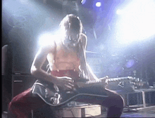 a man is playing a guitar on stage in front of a crowd .