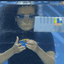 a woman wearing sunglasses is playing with a rubik 's cube in a pool