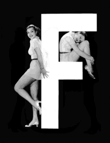 a black and white photo of a woman standing next to a large letter k