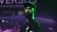 a man wearing glasses and a hat is standing in front of a sign that says " omen "