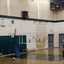 a volleyball game is being played in a gym with a scoreboard showing the time as 88 88
