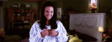 a woman is smiling while standing in a bedroom .