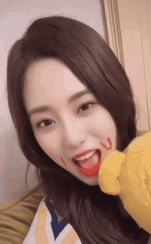 a woman with the letter u painted on her face holds a teddy bear