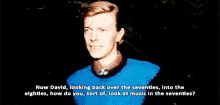 a man in a blue sweater is talking about music