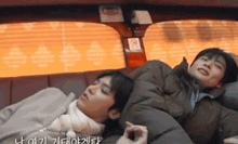 two men are sleeping in a car with a blanket on their heads .