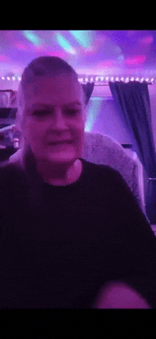 a woman in a black shirt is sitting in front of a disco light