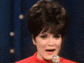 a woman is standing in front of a microphone and smiling .