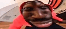 a close up of a person 's face wearing a red hat and making a funny face .