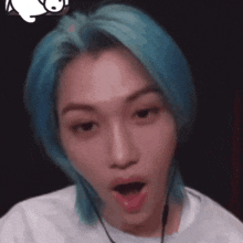 a young man with blue hair is making a funny face .